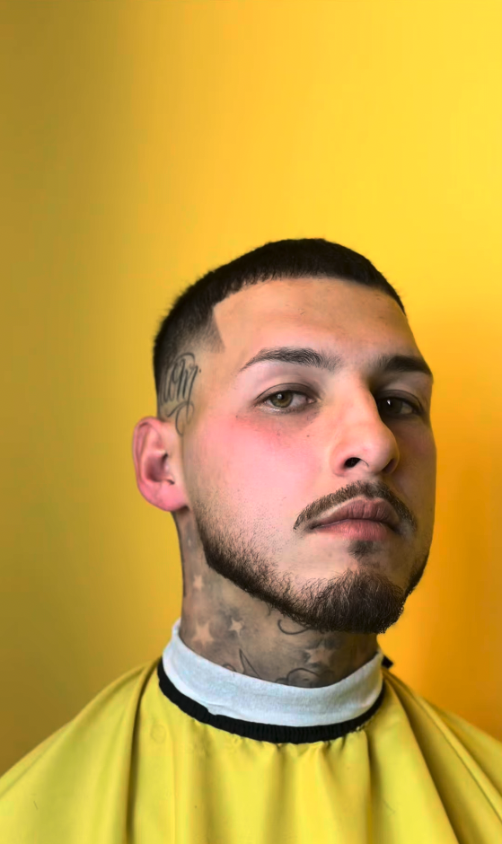 Retrato de cliente com contorno milimétrico do corte e da barba sobre fundo amarelo
