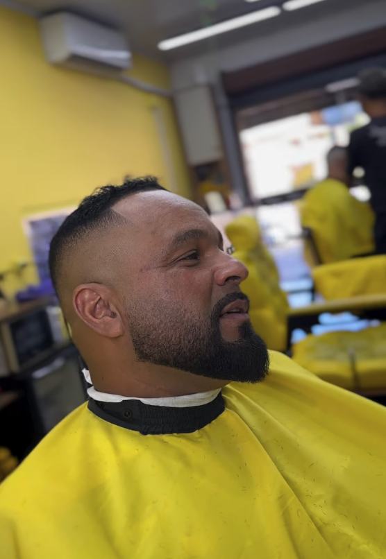 Cliente com barba cheia desenhada e degradê finalizado na cadeira